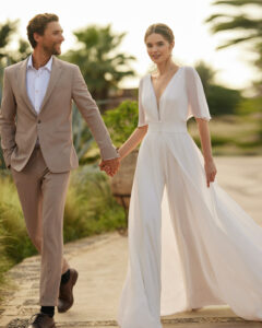 Robe combi de mariée Lara. Une combinaison pantalon sans manche avec manteau amovible pour un effet robe. Collection alma novia 2024