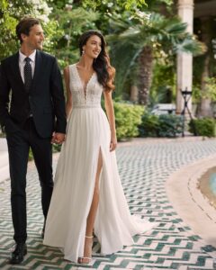 Robe de mariée Alaia guipure et mousseline, col V et dos nu, jupe fendue avec fente. Collection Adriana Alier 2024 boutique mariage paris