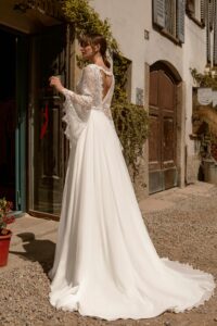 Robe de mariée Emma manches longues forme papillon. Jupe fluide col V à l'avant et dos ouvert en V. Essayer boutique mariage Paris rdv