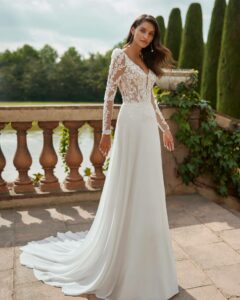 Robe de mariée Daser, nouvelle collection Adriana Alier 2025. Dentelle manches longues et décolleté. Boutique mariage paris showroom RDV