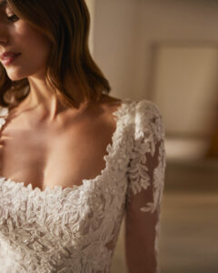 Robe de Mariée Nera collection Alma Novia 2026. Robe col carré manches longues et traîne dentelle. Essayer boutique mariage showroom Paris