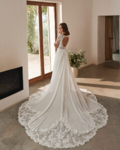 Robe de Mariée Nera collection Alma Novia 2026. Robe col carré manches longues et traîne dentelle. Essayer boutique mariage showroom Paris