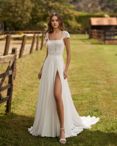 Robe de Mariée Netzer collection Alma Novia 2026. Robe dentelle fluide col carré et petites manches. Essayer boutique mariage showroom Paris