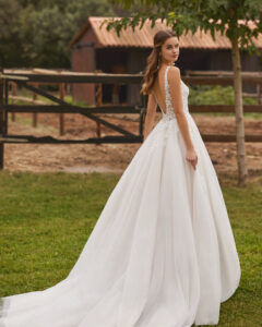 Robe de Mariée Noira collection Alma Novia 2026. Robe tulle dentelle sans manches et dos en V. Essayer boutique mariage showroom Paris