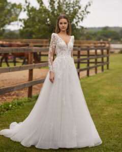 Robe de Mariée Nolir collection Alma Novia 2026. Robe tulle dentelle manches longues et dos en V. Essayer boutique mariage showroom Paris