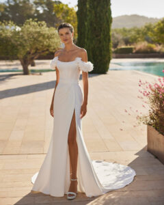 Robe de Mariée Sabila Adriana Alier 2026. Robe bustier stylée grosses fleurs blanches épaules tombantes. Essayer boutique mariage Paris