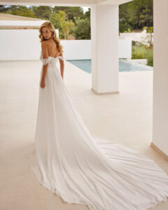 Robe de Mariée Sandalo Adriana Alier 2026. Robe bustier stylée grosses fleurs blanches épaules tombantes. Essayer boutique mariage Paris
