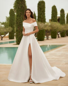 Robe de Mariée Sulina Adriana Alier 2026. Robe volume simple mikado sans dentelle, col bardot et fendue. Essayer boutique mariage Paris
