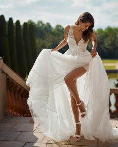 Robe de Mariée Delia Adriana Alier 2026. Robe dentelle volume fente fendue manches longues amovibles. Essayer RDV boutique mariage Paris