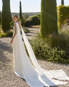 Robe de Mariée Mongolia Alma Novia 2027 col américain croisé avec pans traine sans dentelle chic. A essayer à Paris sur RDV boutique mariage