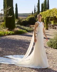 Robe de Mariée Mongolia Alma Novia 2027 col américain croisé avec pans traine sans dentelle chic. A essayer à Paris sur RDV boutique mariage