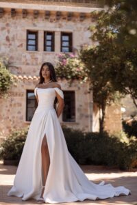 Robe de mariée luna cosmobella 2027. Robe bustier en satin fendue et manches tombantes amovibles. RDV essayage boutique mariage Paris