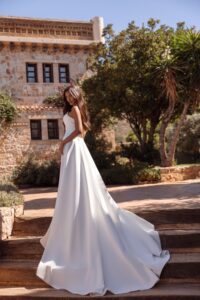 Robe de mariée luna cosmobella 2027. Robe bustier en satin fendue et manches tombantes amovibles. RDV essayage boutique mariage Paris